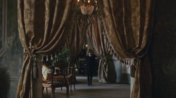 Movie still from “The Childhood of a Leader” (2015), directed by Brady Corbet – A woman is walking through a room with a chandelier; Wide shot, Low angle