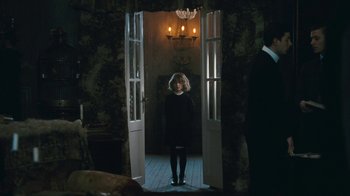 Movie still from “The Childhood of a Leader” (2015), directed by Brady Corbet – A woman standing in front of a door way; Wide shot, Over the shoulder angle