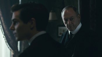 Movie still from “The Childhood of a Leader” (2015), directed by Brady Corbet – A man in a suit and tie standing next to another man in a suit and tie; Close Up shot, Over the shoulder angle