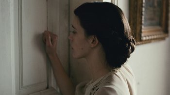 Movie still from “The Childhood of a Leader” (2015), directed by Brady Corbet – A woman leaning against a wall with her hand on the wall; Close Up shot, Over the shoulder angle