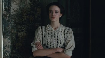 Movie still from “The Childhood of a Leader” (2015), directed by Brady Corbet – A woman in a white shirt with her arms crossed; Medium shot, Over the shoulder angle