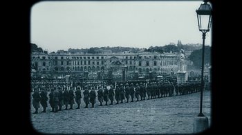 Movie still from “The Childhood of a Leader” (2015), directed by Brady Corbet – An old photo of a parade of soldiers marching down a street; Extreme Wide shot, High angle