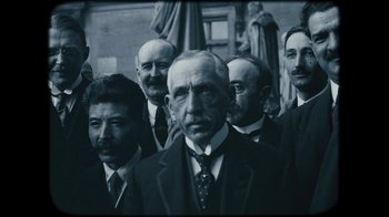 Movie still from “The Childhood of a Leader” (2015), directed by Brady Corbet – A black and white photo of a group of men in suits; Medium shot, Low angle