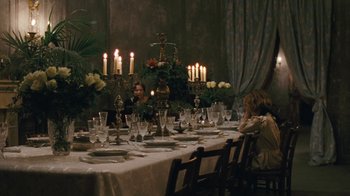 Movie still from “The Childhood of a Leader” (2015), directed by Brady Corbet – People sitting at a dinner table with candles lit up; Wide shot, High angle