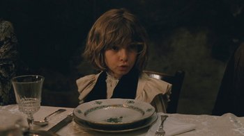Movie still from “The Childhood of a Leader” (2015), directed by Brady Corbet – A young child sitting at a table with a plate of food; Close Up shot, Over the shoulder angle