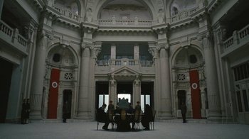 Movie still from “The Childhood of a Leader” (2015), directed by Brady Corbet – A group of people sitting around a table in a large room; Extreme Wide shot, High angle