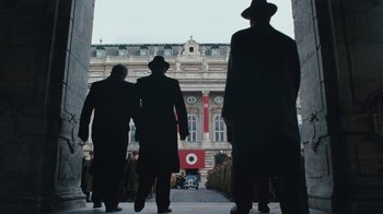 Movie still from “The Childhood of a Leader” (2015), directed by Brady Corbet – A group of men walking down a sidewalk; Wide shot, Low angle