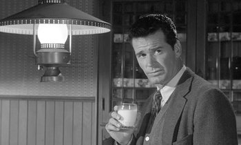 Movie still from “The Children's Hour” (1961), directed by William Wyler – A black and white photo of a man holding a glass of milk; Medium shot, Low angle