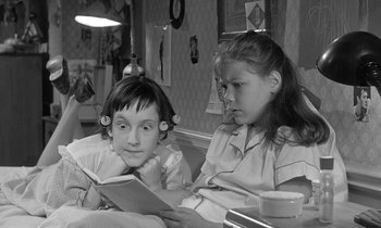 Movie still from “The Children's Hour” (1961), directed by William Wyler – Two young girls sitting at a table reading a book; Close Up shot, Over the shoulder angle