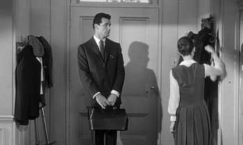 Movie still from “The Children's Hour” (1961), directed by William Wyler – A black and white photo of a man holding a briefcase; Medium shot, Over the shoulder angle
