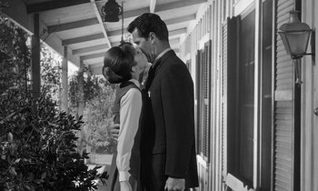 Movie still from “The Children's Hour” (1961), directed by William Wyler – A man and a woman kissing on the side of a house; Medium shot, Low angle