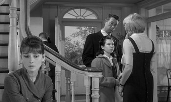 Movie still from “The Children's Hour” (1961), directed by William Wyler – A group of people standing on a set of stairs; Medium shot, Over the shoulder angle