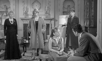 Movie still from “The Children's Hour” (1961), directed by William Wyler – A group of people in a living room with a fire place; Wide shot, Over the shoulder angle
