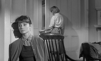 Movie still from “The Children's Hour” (1961), directed by William Wyler – A woman sitting on a chair in front of a door; Medium shot, Over the shoulder angle