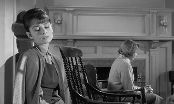Movie still from “The Children's Hour” (1961), directed by William Wyler – A woman sitting in a rocking chair with her eyes closed; Medium shot, Over the shoulder angle