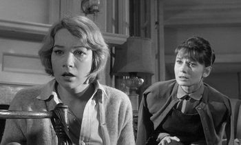 Movie still from “The Children's Hour” (1961), directed by William Wyler – Two people sitting in a living room , one of whom is holding a gun and the other of whom is sitting on a chair; Close Up shot, Low angle