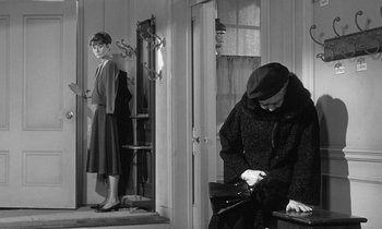Movie still from “The Children's Hour” (1961), directed by William Wyler – A woman in a hat is standing next to a woman in a dress; Medium shot, Over the shoulder angle