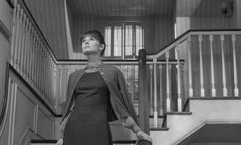 Movie still from “The Children's Hour” (1961), directed by William Wyler – A black and white photo of a woman standing on a staircase; Medium shot, Low angle