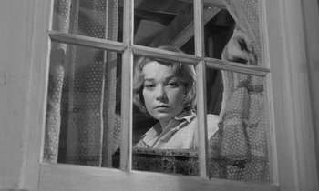 Movie still from “The Children's Hour” (1961), directed by William Wyler – A woman looking out of a window through a lace curtain; Close Up shot, Low angle