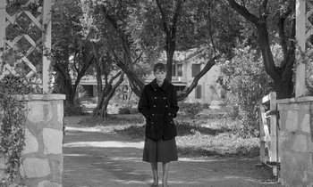 Movie still from “The Children's Hour” (1961), directed by William Wyler – A woman standing in a wooded area with her hands in her pockets; Wide shot, High angle