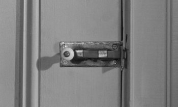 Movie still from “The Children's Hour” (1961), directed by William Wyler – A door lock on a gray door; Extreme Close Up shot, High angle
