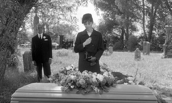 Movie still from “The Children's Hour” (1961), directed by William Wyler – An old photo of a woman standing at a funeral; Medium shot, Over the shoulder angle