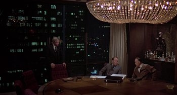 Movie still from “The China Syndrome” (1979), directed by James Bridges – A group of people sitting around a table in front of a large window; Wide shot, Over the shoulder angle