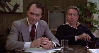 Movie still from “The China Syndrome” (1979), directed by James Bridges – Two men sitting at a table with a glass of water; Medium shot, Over the shoulder angle
