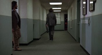 Movie still from “The China Syndrome” (1979), directed by James Bridges – A man in a suit walking down a hallway; Wide shot, High angle