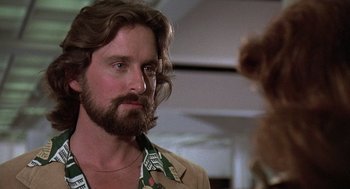 Movie still from “The China Syndrome” (1979), directed by James Bridges – A man with long hair and a beard standing next to a dog; Close Up shot, Over the shoulder angle