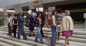 Movie still from “The China Syndrome” (1979), directed by James Bridges – A group of people walking down a street holding signs; Medium shot, High angle