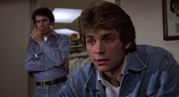 Movie still from “The China Syndrome” (1979), directed by James Bridges – A man in a jean jacket is looking at the camera while another man stands in the background; Close Up shot, Over the shoulder angle