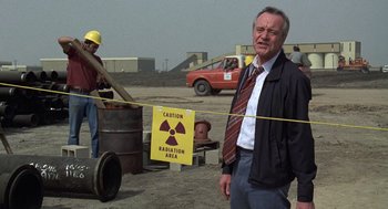 Movie still from “The China Syndrome” (1979), directed by James Bridges – A man standing in front of a sign that says " caution radiation area "; Medium shot, Over the shoulder angle