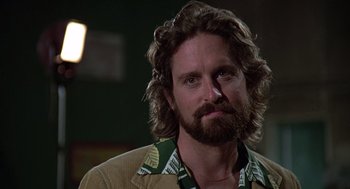 Movie still from “The China Syndrome” (1979), directed by James Bridges – A man with long hair and a beard wearing a suit; Close Up shot, Low angle