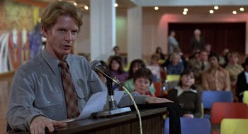 Movie still from “The China Syndrome” (1979), directed by James Bridges – A man is speaking at a microphone in front of a crowd; Medium shot, Over the shoulder angle