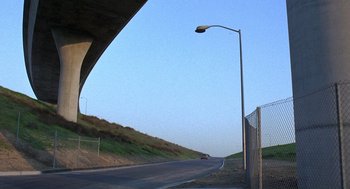 Movie still from “The China Syndrome” (1979), directed by James Bridges – A car is driving down the road under a bridge; Extreme Wide shot, Low angle
