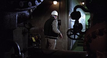 Movie still from “The China Syndrome” (1979), directed by James Bridges – A man wearing a white hard hat and a jacket; Wide shot, Low angle