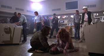 Movie still from “The China Syndrome” (1979), directed by James Bridges – A group of people standing around a man laying on the ground; Wide shot, Low angle