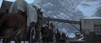 Movie still from “The Claim” (2000), directed by Michael Winterbottom – A group of people riding on top of a covered wagon; Wide shot, Low angle