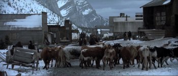 Movie still from “The Claim” (2000), directed by Michael Winterbottom – A herd of cattle standing on top of a snow covered ground; Wide shot, High angle