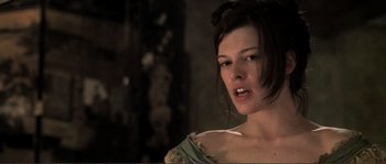 Movie still from “The Claim” (2000), directed by Michael Winterbottom – A woman in a green and white dress looking at the camera; Close Up shot, Low angle