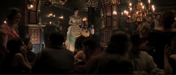 Movie still from “The Claim” (2000), directed by Michael Winterbottom – A man and a woman are standing in front of an audience; Wide shot, Low angle