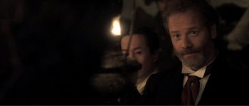 Movie still from “The Claim” (2000), directed by Michael Winterbottom – Two men in a dimly - lit room , one of them holding a candle; Close Up shot, Over the shoulder angle