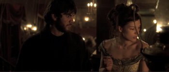 Movie still from “The Claim” (2000), directed by Michael Winterbottom – A man and a woman standing next to each other in a room; Medium shot, Over the shoulder angle