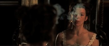 Movie still from “The Claim” (2000), directed by Michael Winterbottom – A woman smoking a cigarette in front of a mirror; Close Up shot, Over the shoulder angle