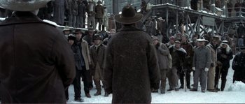 Movie still from “The Claim” (2000), directed by Michael Winterbottom – A group of men standing in the snow; Wide shot, Over the shoulder angle