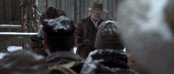 Movie still from “The Claim” (2000), directed by Michael Winterbottom – A man in a brown hat and a brown coat; Medium shot, Over the shoulder angle