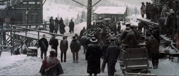 Movie still from “The Claim” (2000), directed by Michael Winterbottom – A group of people standing on top of a snow covered slope; Extreme Wide shot, High angle