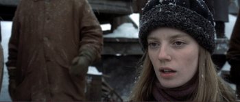 Movie still from “The Claim” (2000), directed by Michael Winterbottom – A young woman wearing a hat and gloves in the snow; Close Up shot, Low angle