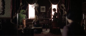Movie still from “The Claim” (2000), directed by Michael Winterbottom – Two women sitting in front of a grand piano in a living room; Wide shot, High angle